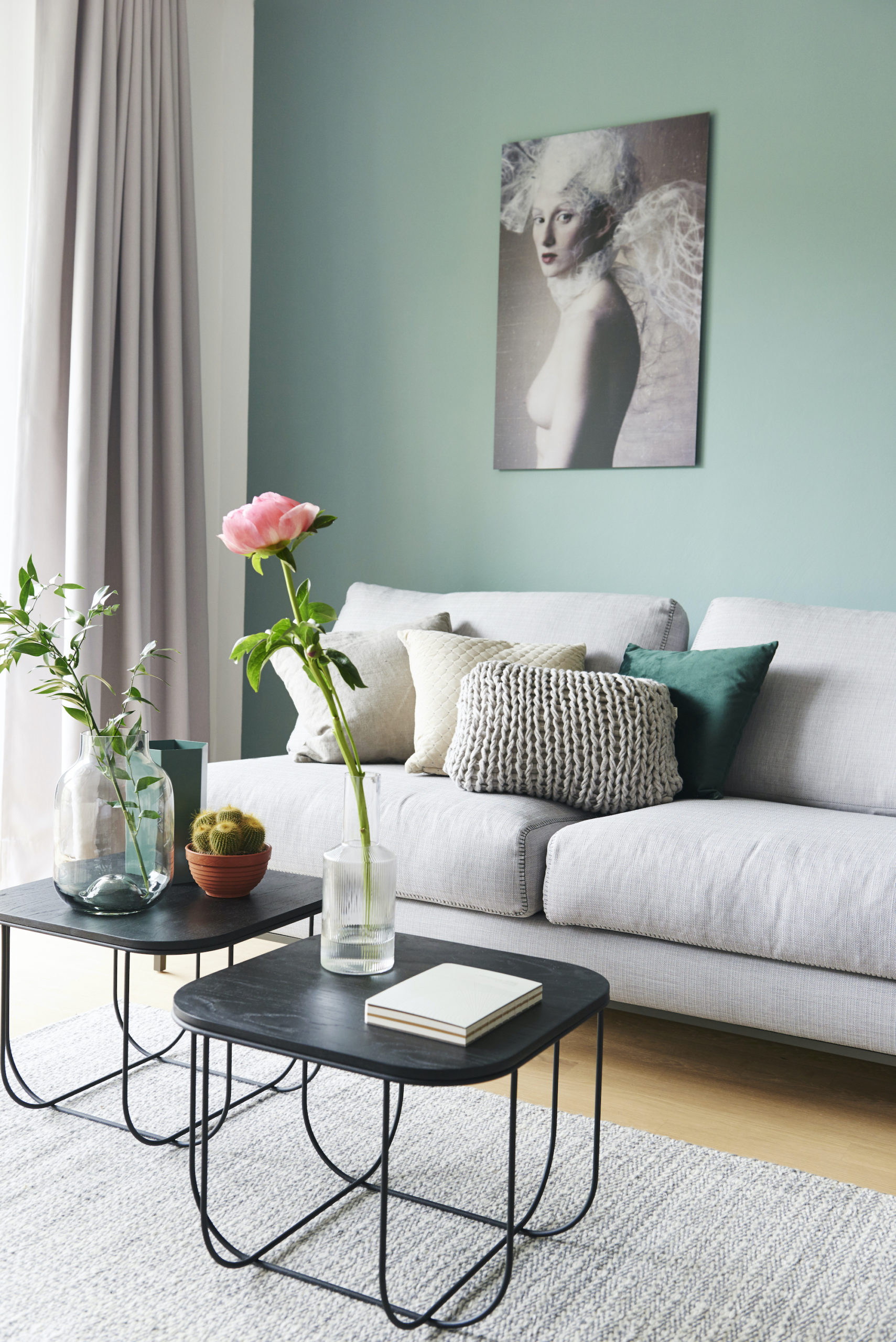 Graues Sofa mit Beistelltisch und Deko vor türkiser Wand