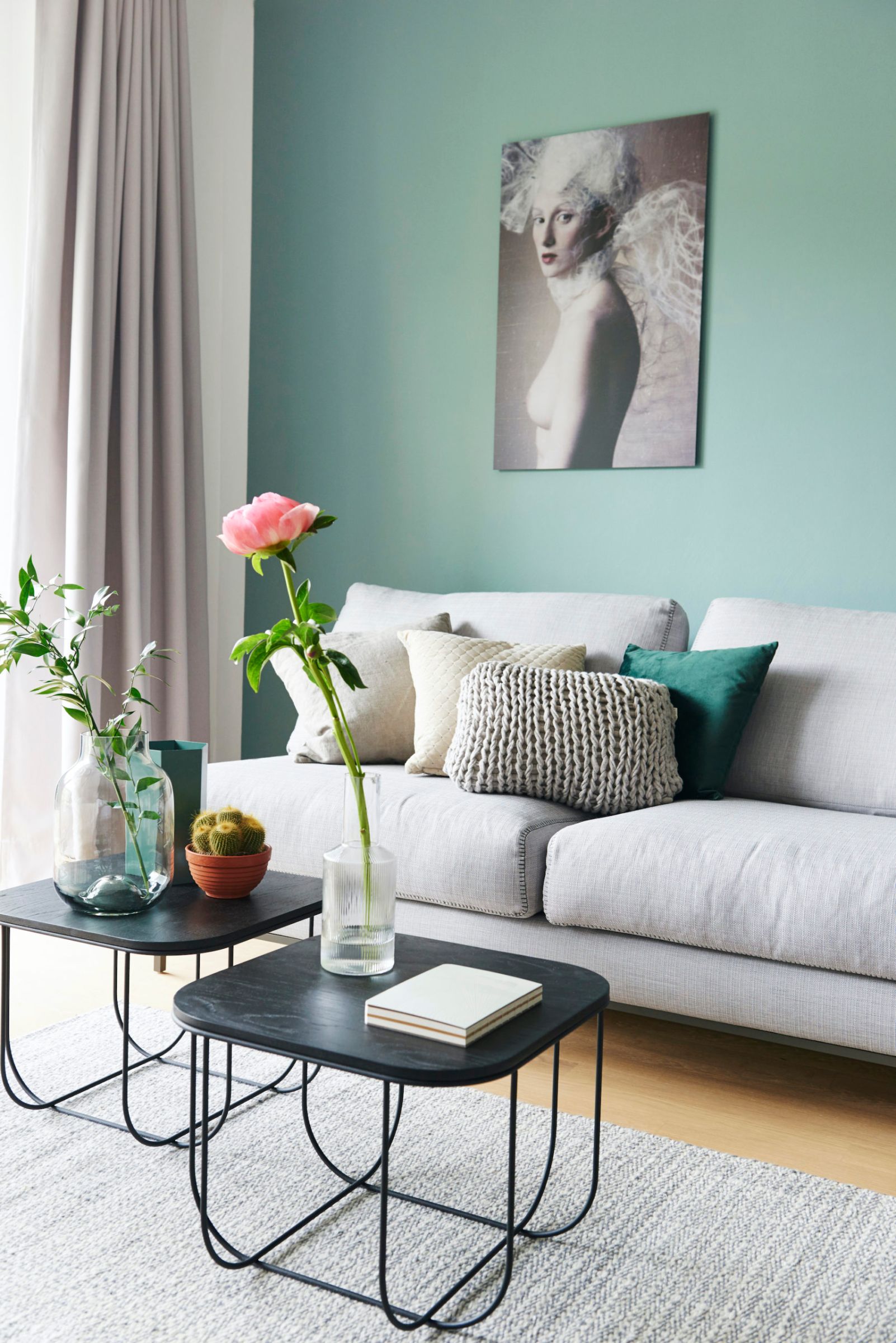 Graues Sofa mit Beistelltisch und Deko vor türkiser Wand
