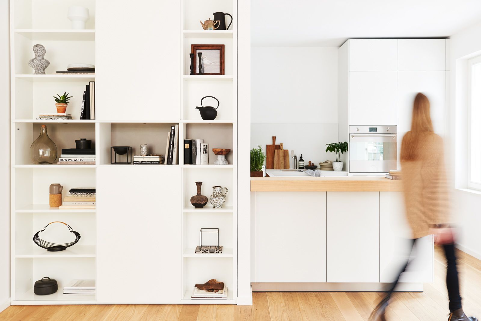 Apartment mit offener Küchenzeile, Holzarbeitsplatte und Regalwand voller Bücher und Deko