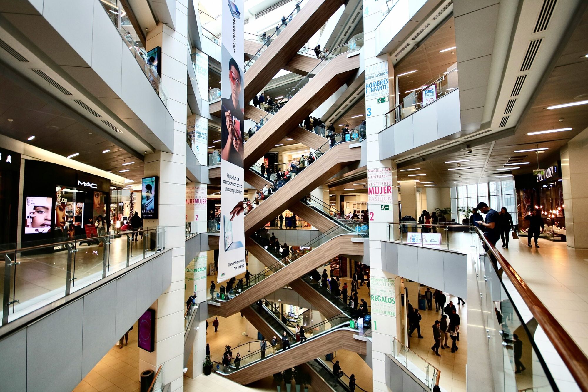 Mehrgeschossiges Einkaufszentrum mit Rolltreppen, Ladenflächen und Besuchern